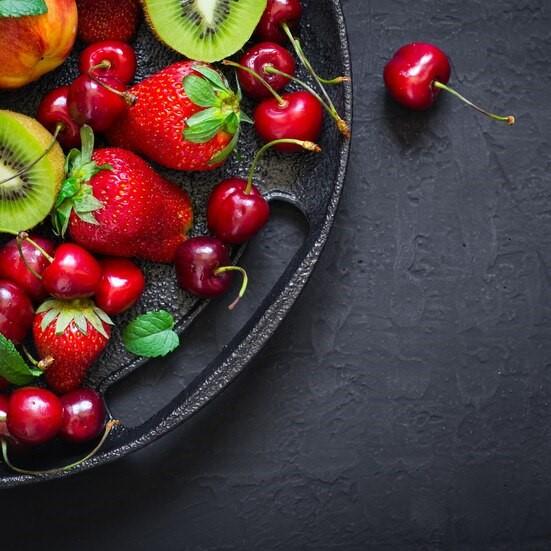 Ассорти из сезонных фруктов и ягод, в сопровождении цветов и мяты